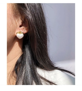 Nahaufnahme eleganter herzförmiger Perlenohrring mit goldener Krone am Model-Ohr