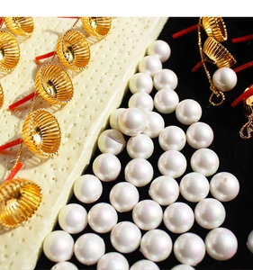 Vue macro de perles blanches lustrées et de supports dorés en forme de coupe pour boucles