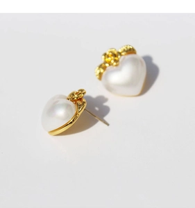Detailansicht der herzförmigen Perlenohrringe mit eleganten goldenen Blütenakzenten