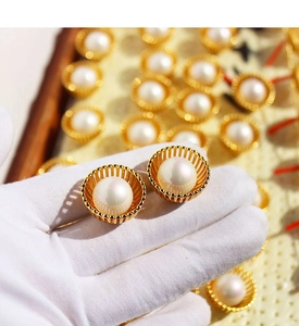 Vue macro de boucles d'oreilles nid doré avec perles brillantes sur gant de bijoutier