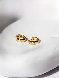 Detailed view of gold-plated bamboo-shaped earrings on a white decorative stone base