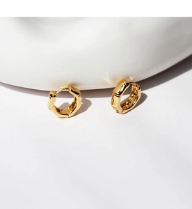 Detail of high-polish gold bamboo texture on minimalist round hoop earrings