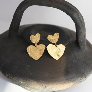 Vintage gold matte earrings with hammered heart pendants on a black ceramic stand