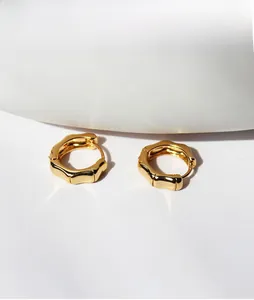 Detailed close-up of gold-plated brass bamboo texture hoop earrings on white background