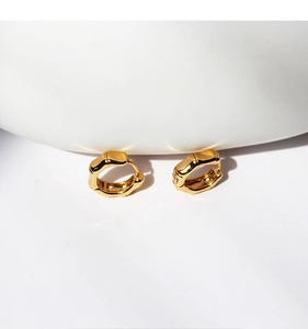 Detailed view of polished gold-plated bamboo textured hoop earrings on white background