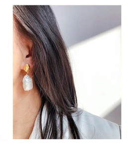 Gros plan de boucles d'oreilles en perles baroques avec clous dorés de forme organique