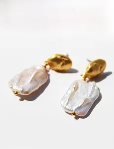 Vue macro de boucles d'oreilles perles baroques avec finition métal doré mat et clou
