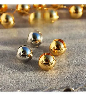 Macro detail of polished brass ball earrings with zircon inlays on grey stone surface