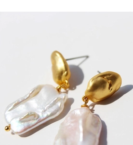 Vue rapprochée des boucles d'oreilles dorées mates avec perles baroques irrégulières