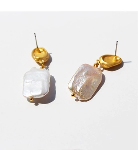 Gros plan sur des perles baroques et boucles d'oreilles dorées à la texture mate élégante