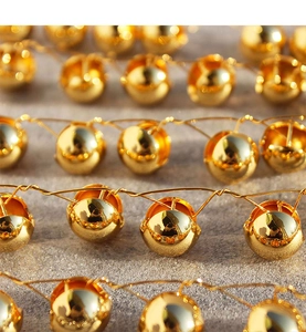 Macro detail of high-shine hollow metal sphere earrings with polished gold mirror finish