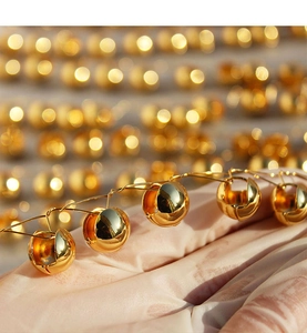 Macro view of polished gold ball earrings with reflective mirror finish and craftsmanship