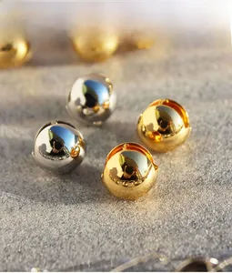 Macro shot of polished gold and silver hollow sphere hoop earrings on stone background