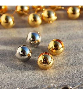 Macro shot of polished hollow spherical stud earrings in gold and silver finish