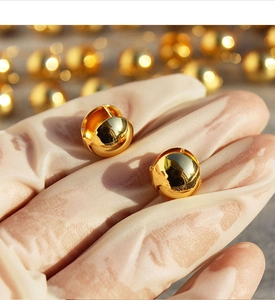 Detailed macro view of gold hollow spherical earrings with high-polish mirror finish surface