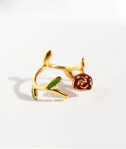 Close-up of vintage red enamel rose flower ring with gold branch detail and green leaves