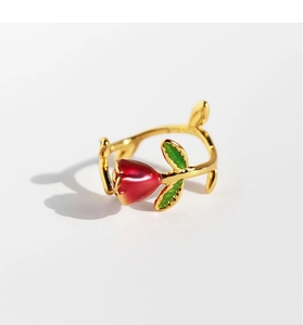 Macro detail of enamel red rose and green leaves on a gold branch style adjustable ring
