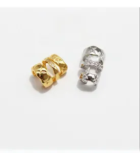 Detail of star-patterned brass ear cuffs plated in gold and white gold with cubic zirconia