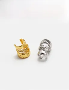 Detail of layered gold and silver ear cuffs with star engravings and zircon stones