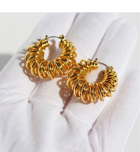 Macro detail of gold-plated spiral hoop earrings showing textured wire winding design