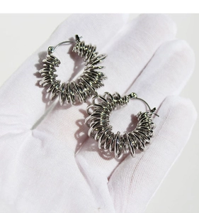 Detail of silver-plated brass spiral hollow spring hoop earrings with a textured finish