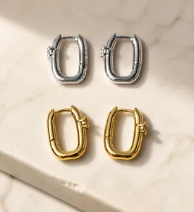 Detail of U-shaped earrings in brass gold and silver plating with premium zircon
