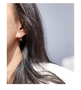 Close-up of minimalist gold U-shape hoop earring with cubic zirconia on model