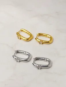 Detail view of gold and silver U-shaped huggie earrings with sparkling cubic zirconia stones