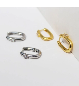 Close-up of minimalist U-shape gold and silver hoop earrings with white zircon stones