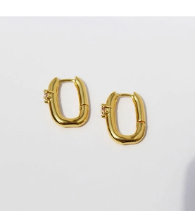 Close-up of gold-plated U-shaped earrings with a delicate pink zircon stone inlay