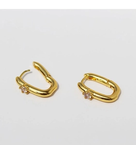 Detailed macro view of U-shaped brass earrings with polished gold finish and zircon stones