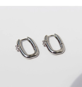Detail of silver U-shaped hoop earrings with zircon stone inlay and secure clasp mechanism