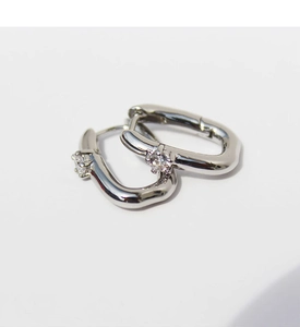 Detailed macro view of silver U-shaped earrings featuring a brilliant round zircon stone