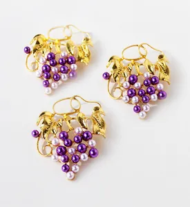 Detail of gold-plated brass grape leaf brooch featuring purple pearls and zircons