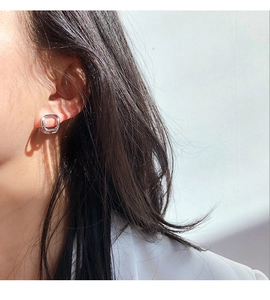 Close-up macro of geometric square hollow silver-plated brass stud earring on a model ear