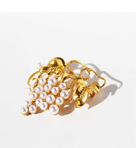 Macro detail of gold-plated brass grape leaf brooch with elegant white imitation pearls
