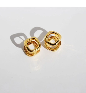 Macro detail of geometric hollow square gold plated earrings with a modern 3D structure