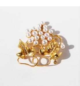 Detailed view of luxury gold-plated grape leaf brooch with elegant white pearls