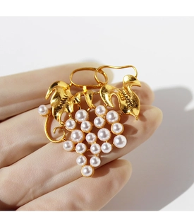 Macro shot of gold-plated grape leaf brooch with elegant white pearls on a sweater