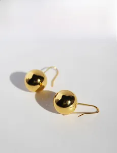 Detailed view of glossy gold sphere earrings with a high-polished mirror finish