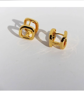 Macro detail of geometric square hollow gold-plated earrings with artistic shadows
