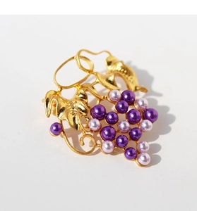 Detailed view of grape brooch featuring gold leaf texture and purple pearl beads