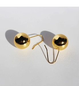 Macro shot of polished gold spherical earrings with mirror finish and ear hook detail