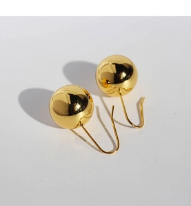 Close-up of polished golden sphere drop earrings with high-gloss mirror finish and hooks