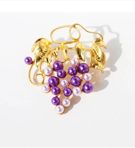Macro detail of brass gold grape brooch with purple pearls and textured leaves