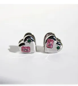 Detailed shot of double-sided heart earrings with pink and green star zircon inlays