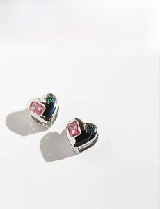 Detail of silver heart earrings with pink zircon, green star stone and black enamel