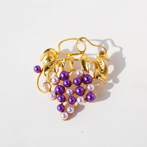 Elegant gold-plated brass grape brooch with purple and pink pearls on white background
