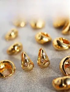 Macro detail of gold teardrop earrings with starburst engraving and micro zircon inlay