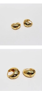 Detail of gold star zircon hoop earrings with polished metal and starburst inlay
